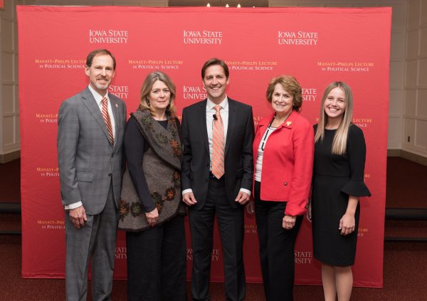 A posed group photo in front of a red banner.